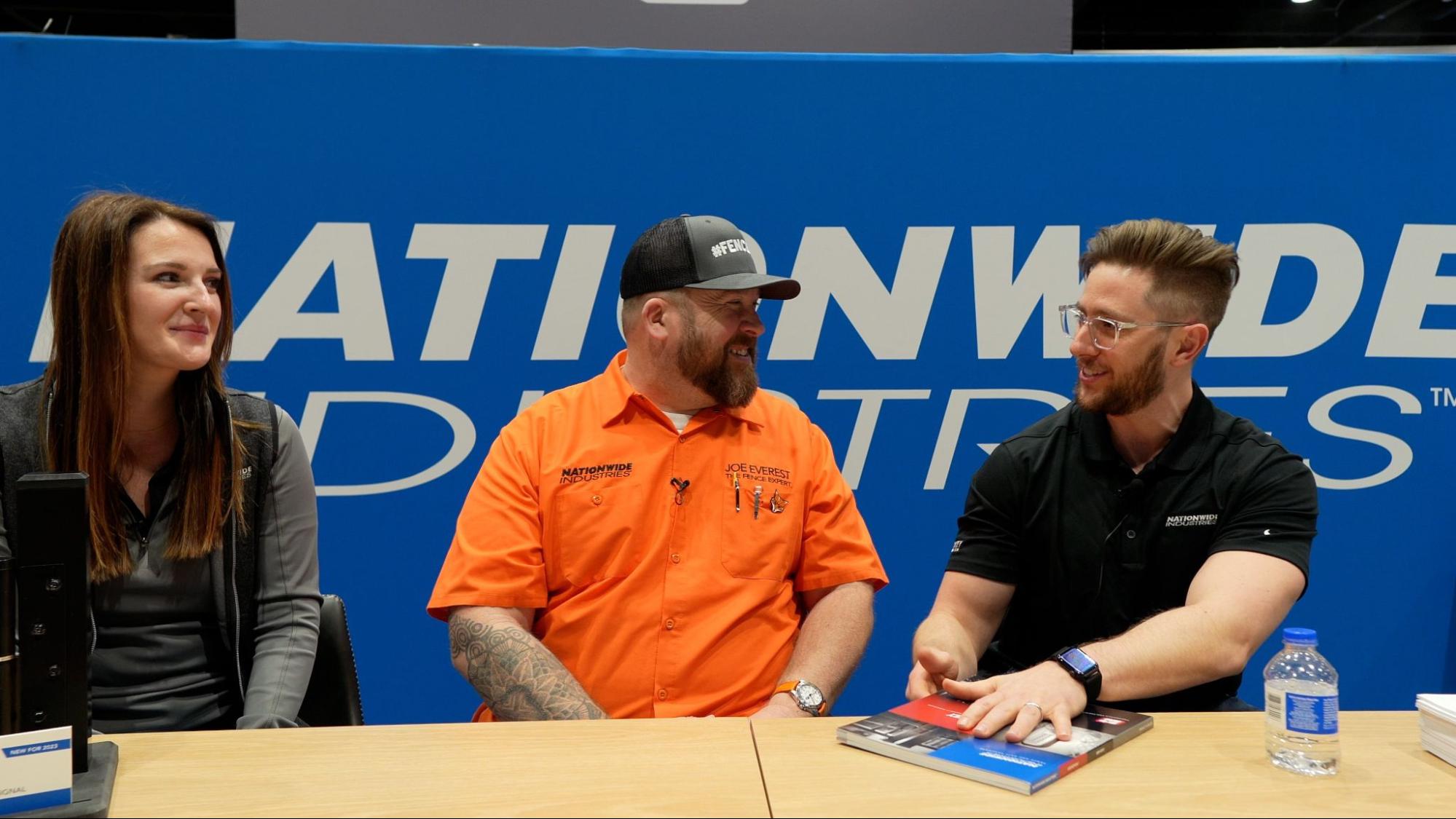 This picture shows three people chatting at a booth. There is a book and a water bottle sitting on the table.